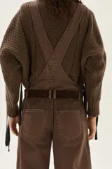 Overol de jean color marrón con calce barrel, tiro medio, pierna ancha y redondeada que termina a la altura del tobillo.