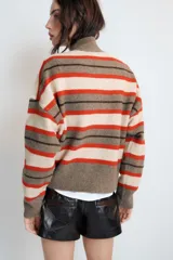 Jersey de punto con diseño de rayas horizontales en tonos gris, rojo y crema. Presenta cuello perkins, cierre frontal con cremallera metálica y mangas largas con hombros caídos.
