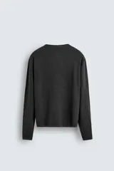 Jersey de manga larga, cuello redondo y calce relajado, color negro con efecto lavado y textura tejida.