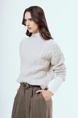 Sweater tejido negro de silueta relajada, con cuello alto y textura trenzada.