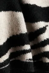 Buzo oversized en punto jacquard con estampado de cebra, cuello redondo y hombros caídos. Presenta terminaciones acanaladas en el cuello, puños y bajo.