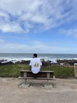 Remera negra de manga corta con cuello redondo y estampado pequeño en el pecho con un diseño abstracto en tonos naranja y amarillo.