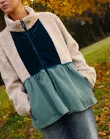 Campera con cierre frontal, confeccionada con patchwork de paño, terciopelo y sherpa color beige, azul y verde. Tiene cuello alto y bolsillos laterales.