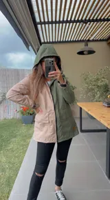 Campera impermeable combinada, mitad color beige y mitad verde militar, con capucha y cierre frontal.