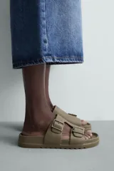 Sandalia tipo slide de goma, color verde militar, con dos tiras anchas ajustables mediante hebillas cuadradas. Presenta plantilla anatómica y suela gruesa con relieve.