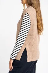 Chaleco de punto color beige con cuello alto y sisas amplias.