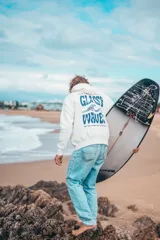 Hoodie de calce holgado en color natural, con capucha y estampado gráfico en la espalda con la frase 'Glassy Waves' en color azul.