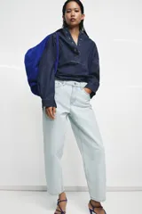 Jeans de tiro alto y silueta tapered, confeccionados en denim negro con costuras en tono contrastante. Cuenta con diseño de cinco bolsillos, trabillas para cinto y cierre frontal con cremallera y botón metálico.