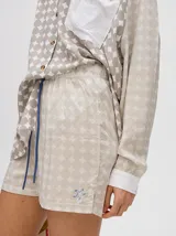 Short de corte boxy confeccionado en viscosa con estampado geométrico de estrellas en tonos rosados. Presenta una pretina elástica en color naranja y cordón de ajuste en color marrón.