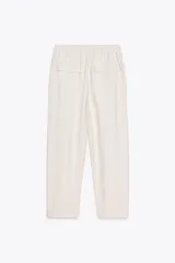 Pantalón tobillero color beige, con cintura elástica ajustable con cordones, bolsillos delanteros y falsos bolsillos con solapa en la espalda.