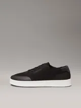Zapatillas de perfil bajo Calvin Klein, confeccionadas en tejido de punto transpirable color negro. Presentan puntera revestida, trabilla trasera de piel y suela de goma blanca con logo grabado en la mediasuela.