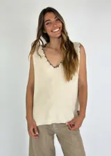 Chaleco de punto color crema con cuello en V y ribete en contraste.
