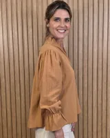 Blusa blanca de algodón con escote en V y cuello mao. Presenta mangas largas abullonadas con puños acampanados y fruncidos.