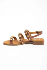 Sandalias planas Lemon de cuero color bronce, con tres tiras frontales adornadas con tachas semiesféricas doradas y cierre de hebilla ajustable en el talón.