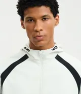 Campera deportiva con capucha, color blanco con recortes laterales en negro. Cuenta con cierre frontal, bolsillos funcionales y ajuste en la cintura.