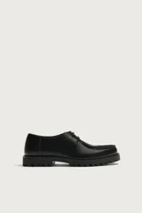 Zapato de cordones de estilo derby, color negro, con parte superior lisa, detalle de bordón en el empeine, horma redonda y suela track dentada.