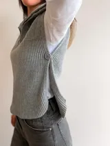 Chaleco de tejido de punto acanalado en color camel, con cuello polo, medio cierre frontal y aberturas laterales con detalle de botones.