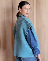 Chaleco tejido de punto color lila, sin mangas y con cuello abierto.