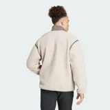 Chaqueta de felpa peluda Adidas Terrex Xploric High Pile de corte holgado, color beige claro con detalles en marrón oscuro en el cuello alto, los ribetes, el cierre frontal y el bolsillo del pecho. Cuenta con bolsillos laterales y un bolsillo con cierre en el pecho.