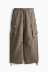 Pantalón cargo de sarga de algodón con efecto lavado, corte holgado y diseño de pierna ancha. Cuenta con cintura elástica con cordón de ajuste, bolsillos laterales, bolsillos traseros con solapa y bolsillos cargo en los muslos. Incluye pliegues en las rodillas y cordón ajustable en el bajo.