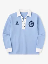 Remera polo celeste de manga larga con cuello y puños blancos, cierre frontal acordonado con ojales metálicos, y detalles bordados en el pecho.