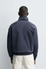 Sudadera de corte relajado color azul marino, con cuello subido y cierre frontal de cremallera. Presenta manga larga, bolsillo frontal tipo canguro y acabados en rib en puños y bajo.