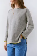 Buzo de tejido de punto color beige, con corte relajado, cuello redondo y mangas largas. Presenta detalles de terminaciones en color azul marino en los puños y en el ruedo inferior.