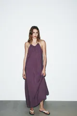 Vestido midi color lila de cuello halter y tirantes finos ajustables en la espalda.