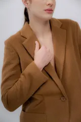 Blazer color camel de baby alpaca, con cuello de solapa, cierre frontal con botones y bolsillos laterales.