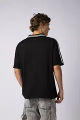 Remera tipo chomba de tejido de punto color blanco, con cuello polo y diseño de rayas verticales sutiles. Presenta estampado gráfico frontal con texto y logo, además de detalles de rayas negras en los hombros.