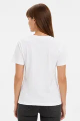 Remera blanca de manga corta y cuello redondo, confeccionada en algodón, con un diseño holgado y estampado frontal de estrella roja con textura y detalles de estrellas pequeñas.