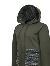 Buzo tipo campera de algodón orgánico color verde militar, con cierre frontal de botones a presión, capucha forrada con estampado étnico y bolsillos frontales con detalles de tejido aguayo multicolor.