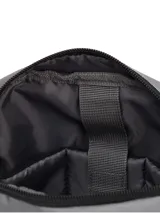 Bolso tipo bandolera Caterpillar color gris, con correa ajustable negra, compartimento principal con cierre, bolsillo frontal vertical con cremallera y detalles de la marca en amarillo y negro.