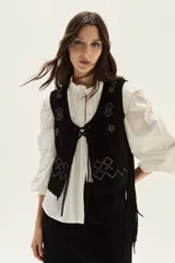 Chaleco de cuero negro con flecos largos en los laterales y detalles bordados en hilo blanco en la espalda.