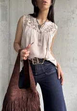 Blusa beige sin mangas con detalle de encaje en el cuello y botones en el frente.