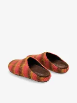 Clog tipo mula con diseño de textura peluda y estampado degradado en tonos violeta, negro y rosa. Presenta una silueta cerrada en la parte frontal y abierta en el talón.