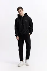 Pantalón de jogging negro de algodón y poliéster, con puños ajustados en los tobillos, cintura elástica con cordón y costuras verticales marcadas en el frente.