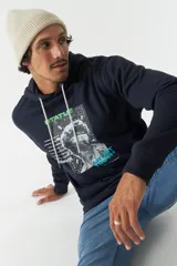 Canguro de felpa color tostado, con capucha, cordones de ajuste negros, bolsillo tipo canguro y estampado gráfico frontal inspirado en el arte clásico.