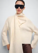 Jersey de punto color marfil con cuello alto y bufanda integrada del mismo tejido y textura acanalada, de diseño holgado y manga larga.