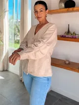 Chaqueta de punto color beige con escote en V, cierre frontal con botones metálicos y mangas largas con diseño holgado.
