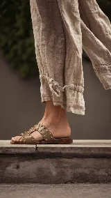 Sandalias planas de cuero negro, con diseño de tiras anchas interconectadas y punta cuadrada, decoradas con tachas metálicas doradas.