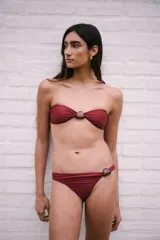 Conjunto de bikini bordeaux con corpiño tipo bandeau con piedra en el centro y bombacha colaless con piedra en el lateral.