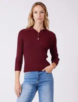 Buzo de tejido acanalado marca Rio & Rian, color bordó, con cuello polo con solapa y cierre frontal de tres botones. Presenta mangas tres cuartos y un ajuste al cuerpo.