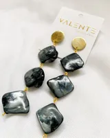 Aros colgantes con base dorada y piedras rectangulares nacaradas en tonos grises y negros, unidas por argollas doradas.