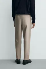 Pantalón de corte regular fit, color negro, confeccionado en tejido elástico. Presenta cintura elástica, cierre frontal con cremallera y botón, bolsillos laterales y bolsillos traseros de vivo.