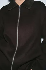 Chaqueta de corte recto confeccionada en hilatura con lana, en color marrón oscuro. Presenta cuello clásico en tejido efecto piel de ante, cierre frontal con cremallera metálica y manga larga.