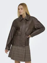 Campera de cuero sintético color marrón con cuello camisero, cierre frontal oculto con botones a presión y bolsillos delanteros con solapa. Presenta un diseño de corte recto y acabado con textura suave.