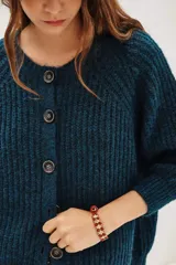 Cardigan de punto grueso acanalado color azul, con cuello redondo, cierre frontal de botones y mangas largas.