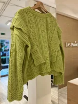Sweater verde claro de tejido de punto calado con volados laterales.