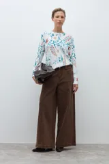 Sweater de punto fino con estampado floral en tonos azules, naranjas y verdes sobre base color crudo. Presenta cuello redondo y mangas largas.